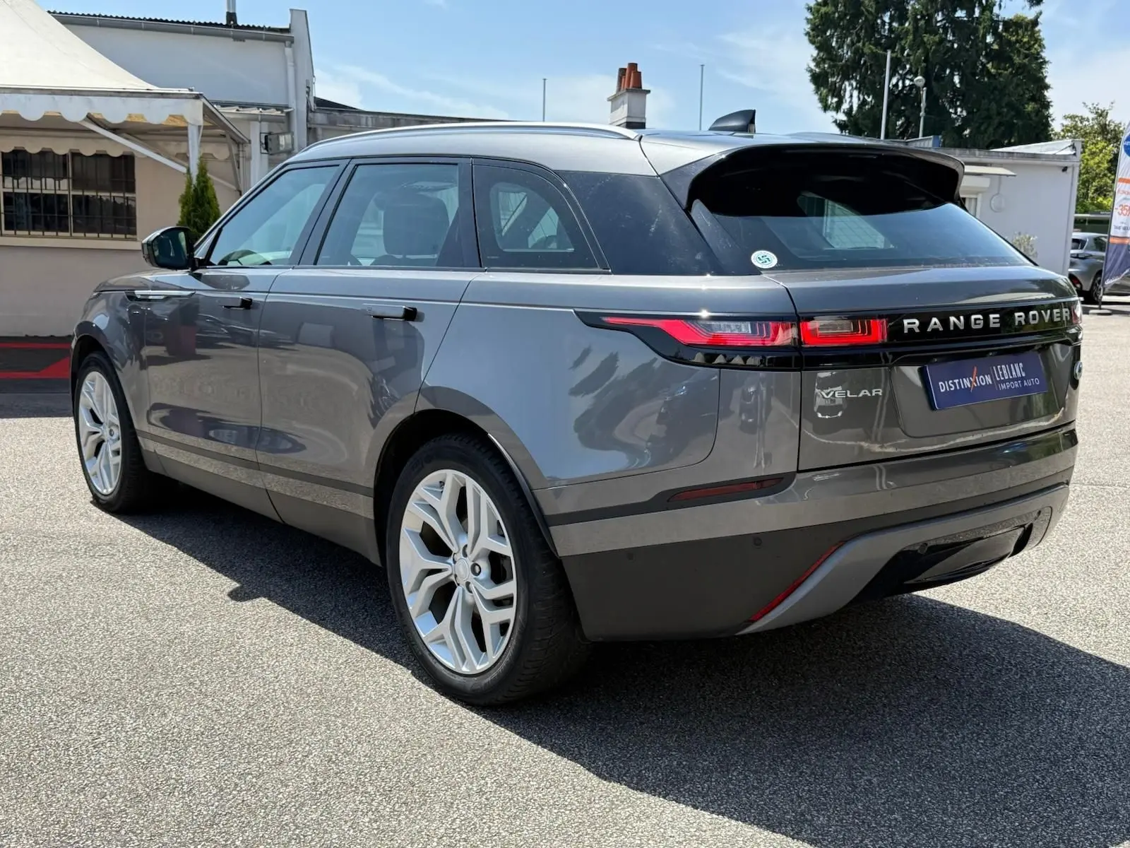 Range Rover Velar gris en 3/4 arrière droit, avec feux LED et jantes alliage distinctives visibles.