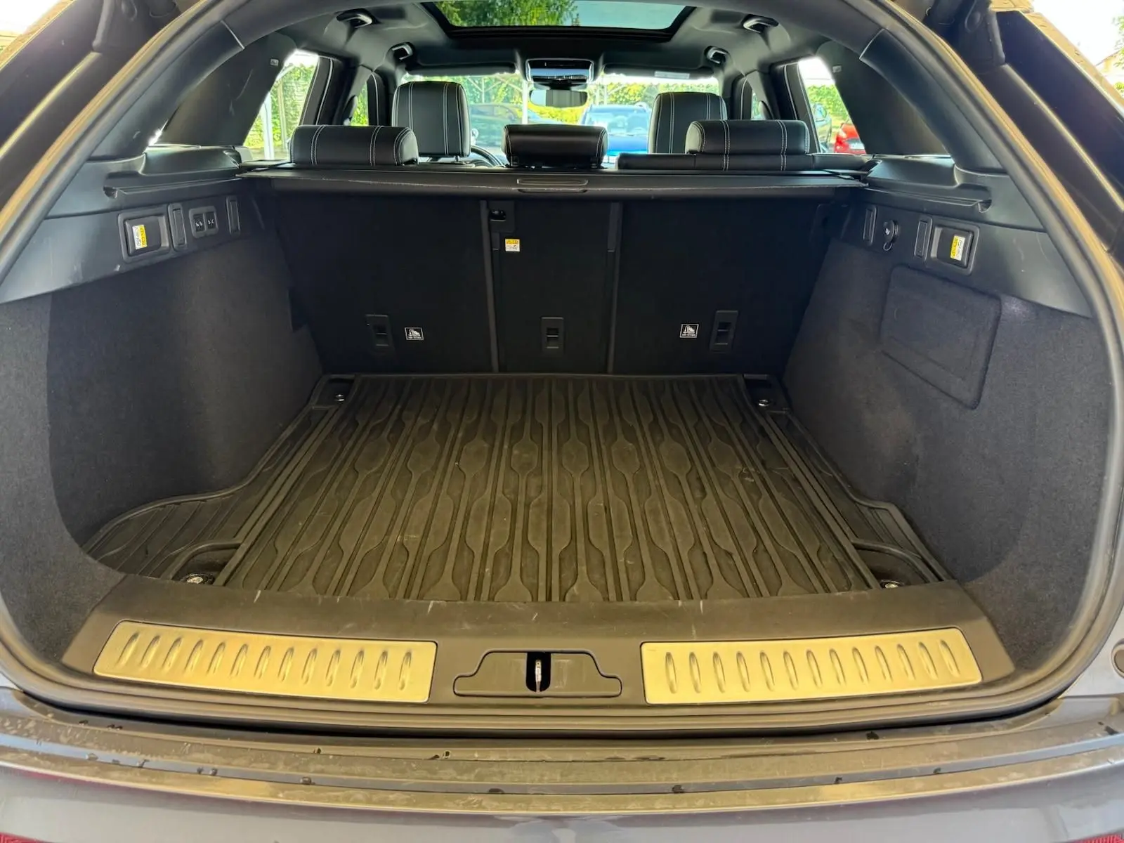 Coffre ouvert d'un Range Rover Velar gris 2019, vue arrière montrant la moquette et les sièges arrière en cuir noir.