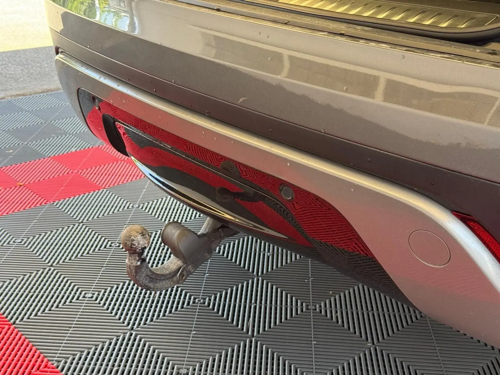 Gros plan sur l'attelage arrière du Range Rover Velar gris, soulignant le pare-chocs et le feu arrière droit.