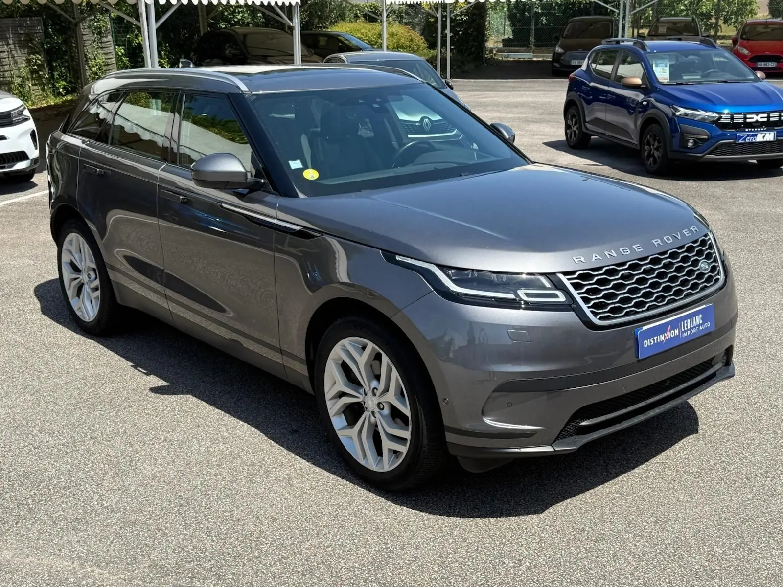 Vue 3/4 avant d'un Range Rover Velar gris métallisé, soulignant sa calandre distinctive et ses jantes argentées élégantes.