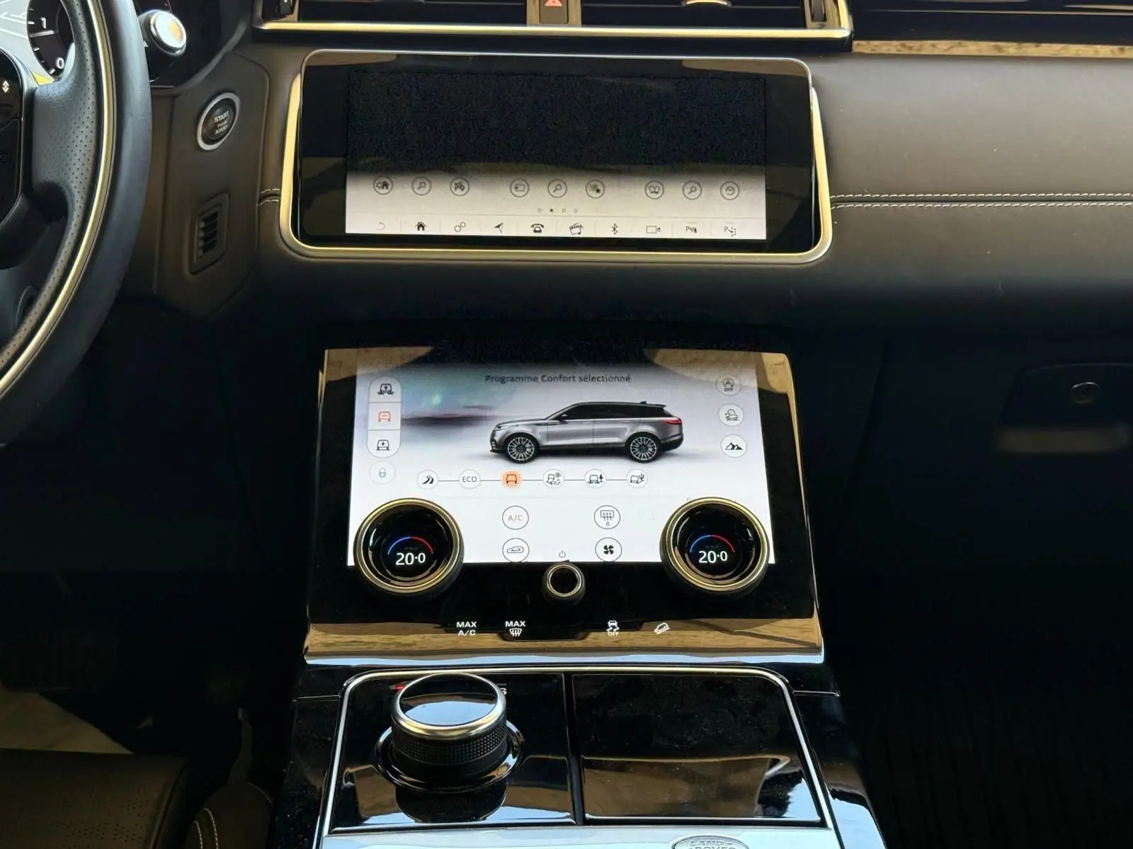 Vue rapprochée du tableau de bord du Range Rover Velar gris, mettant en valeur l'écran tactile central et les commandes de climatisation.