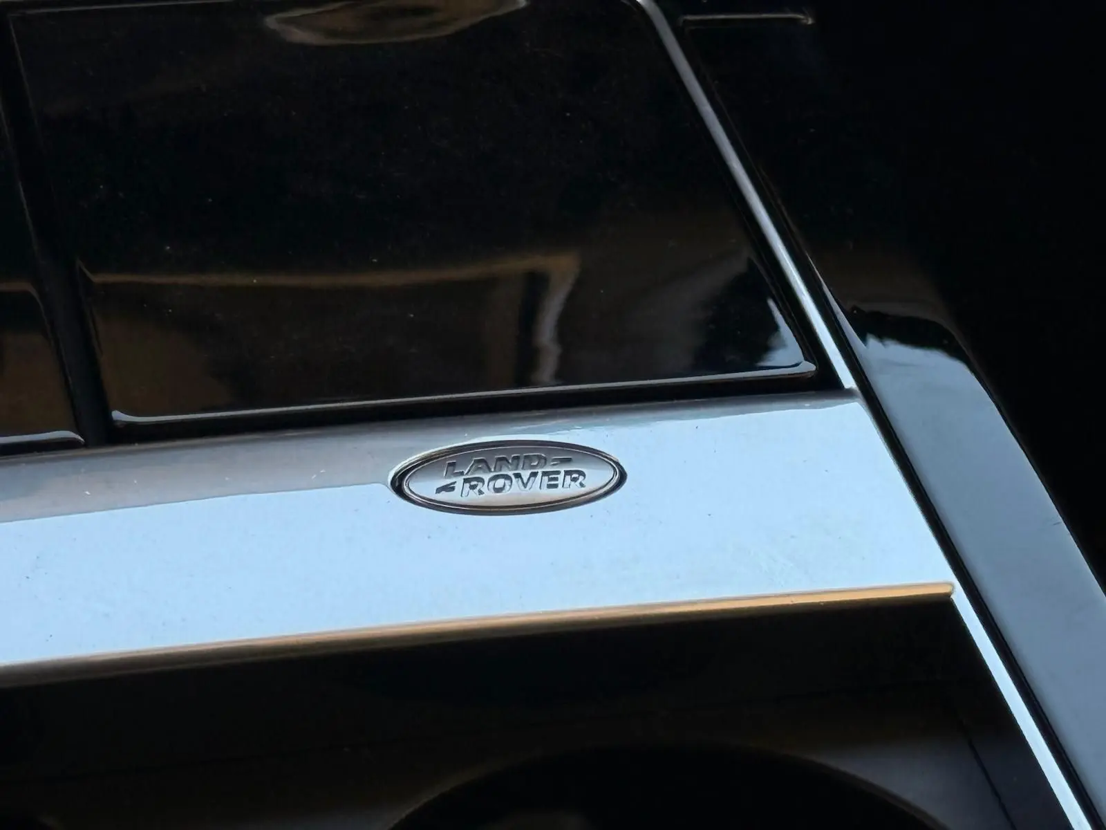 Gros plan sur le logo Land Rover chromé sur la console centrale noire brillante du Range Rover Velar gris 2019.