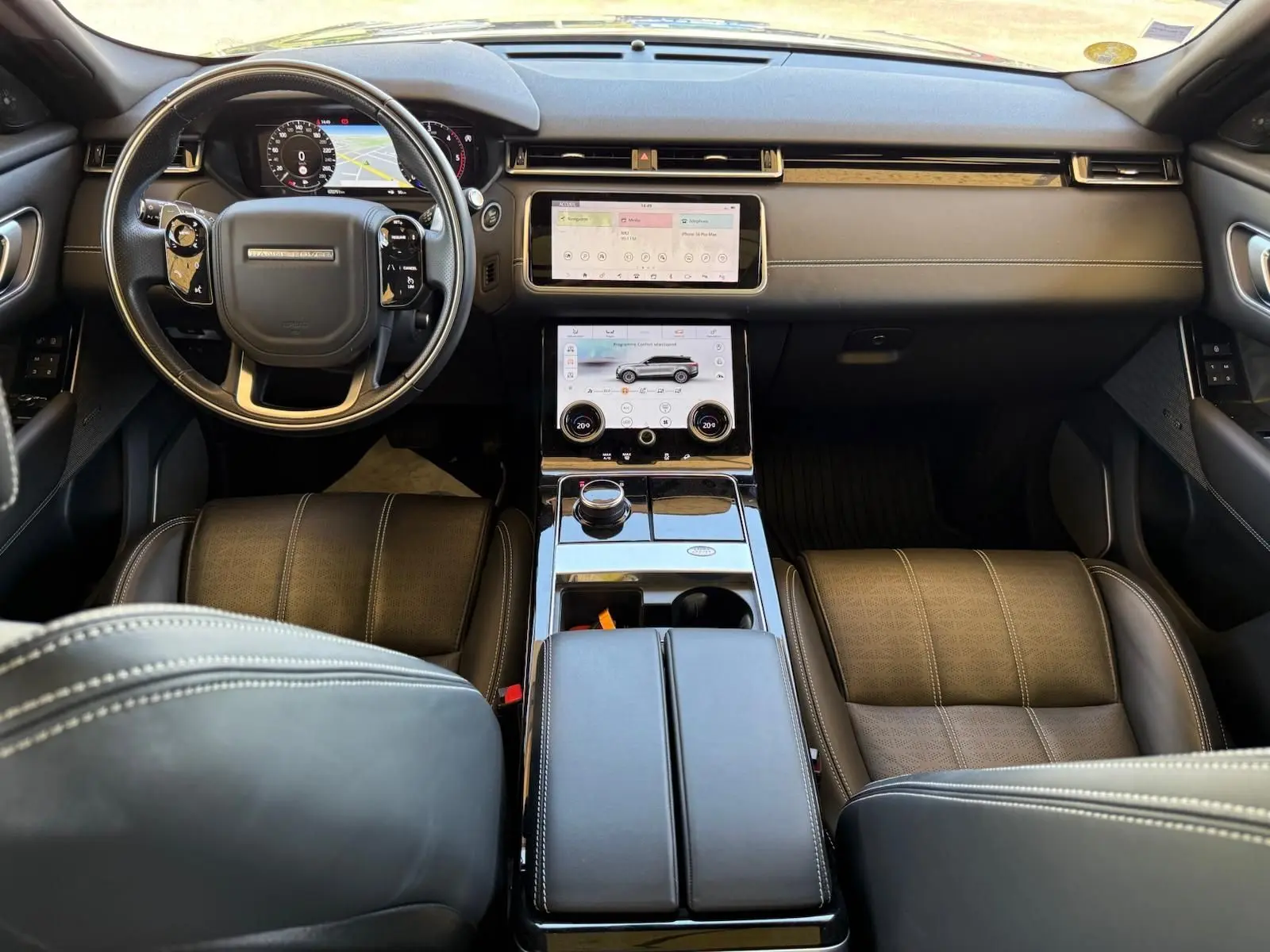 Vue intérieure avant du Range Rover Velar 2019, avec tableau de bord en cuir marron et écran tactile central double.