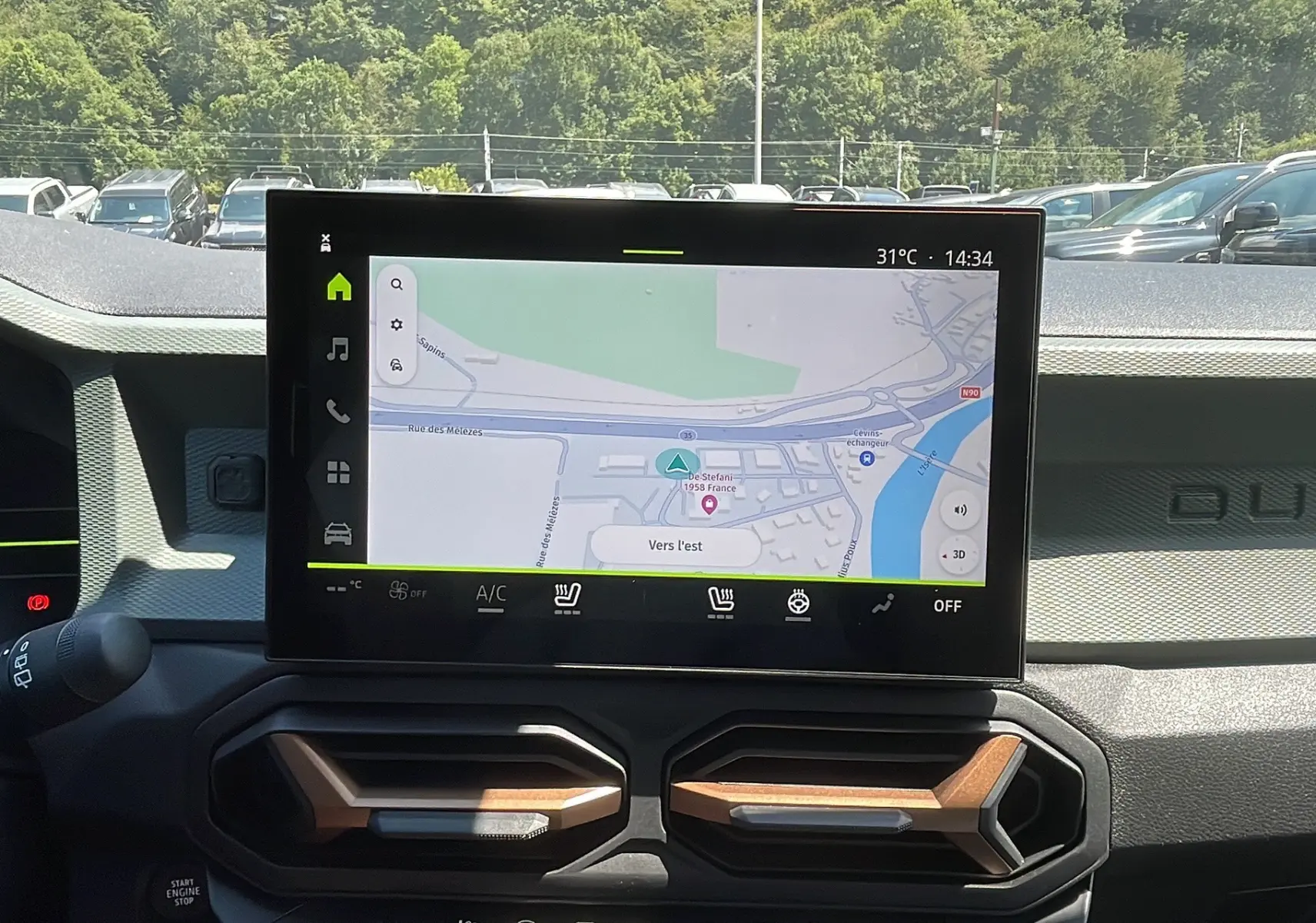 Vue intérieure du tableau de bord du Dacia Duster 2025 avec écran tactile affichant la navigation et aérateurs design.