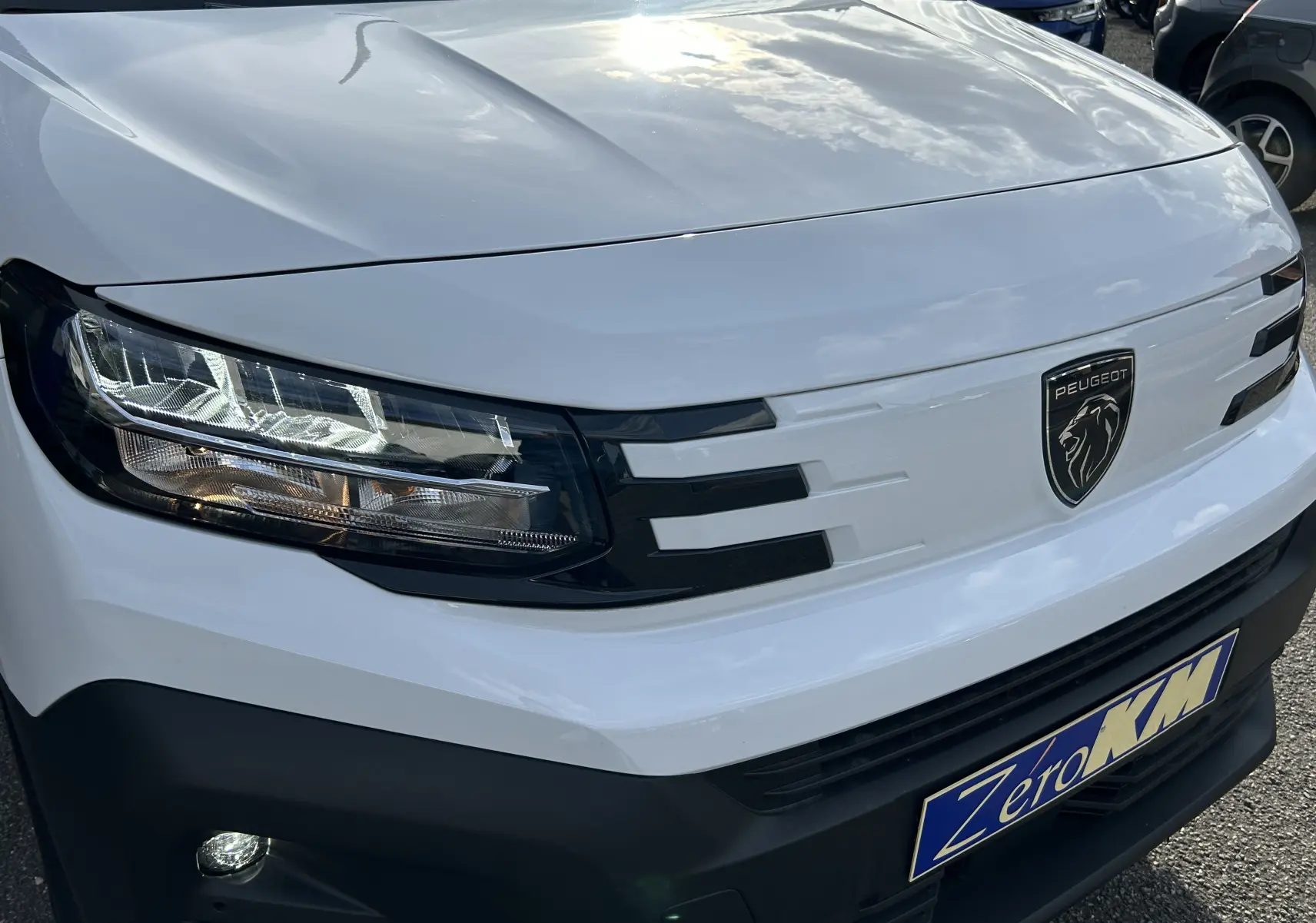 Gros plan sur l'avant blanc du Peugeot Partner Fourgon 2025 avec calandre noire et logo lion central.
