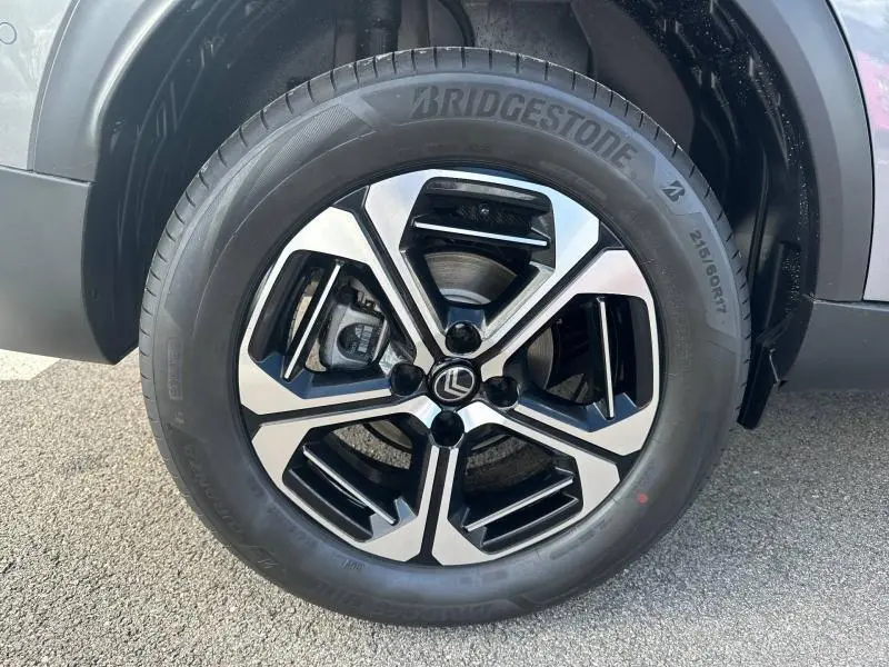 Gros plan sur la roue avant droite du Citroën C3 Aircross gris Mercury, jante alliage noire et argentée, pneu Bridgestone.
