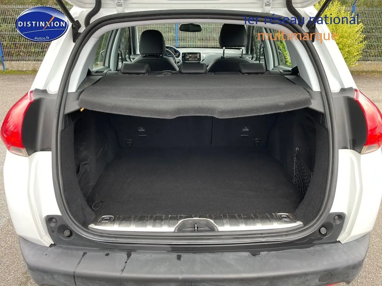 Coffre ouvert vu de l'arrière d'un Peugeot 2008 blanc nacré, montrant l'espace de chargement et la plage arrière.