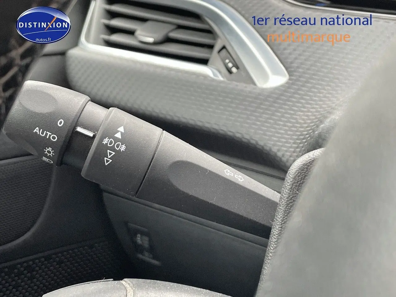 Gros plan sur la manette des feux et clignotants du tableau de bord d'un Peugeot 2008 blanc nacré de 2015.