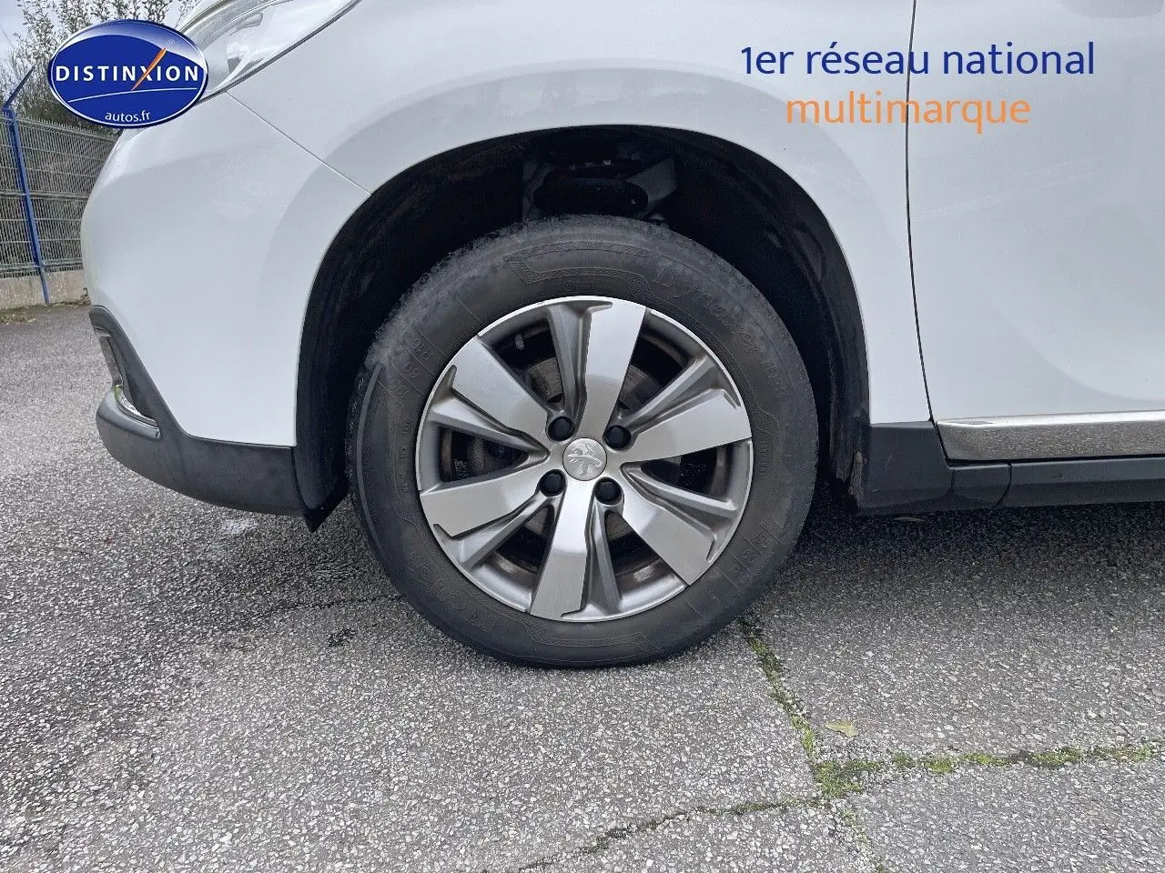 Gros plan sur la roue avant gauche d'un Peugeot 2008 blanc nacré, mettant en valeur la jante alliage et le passage de roue.