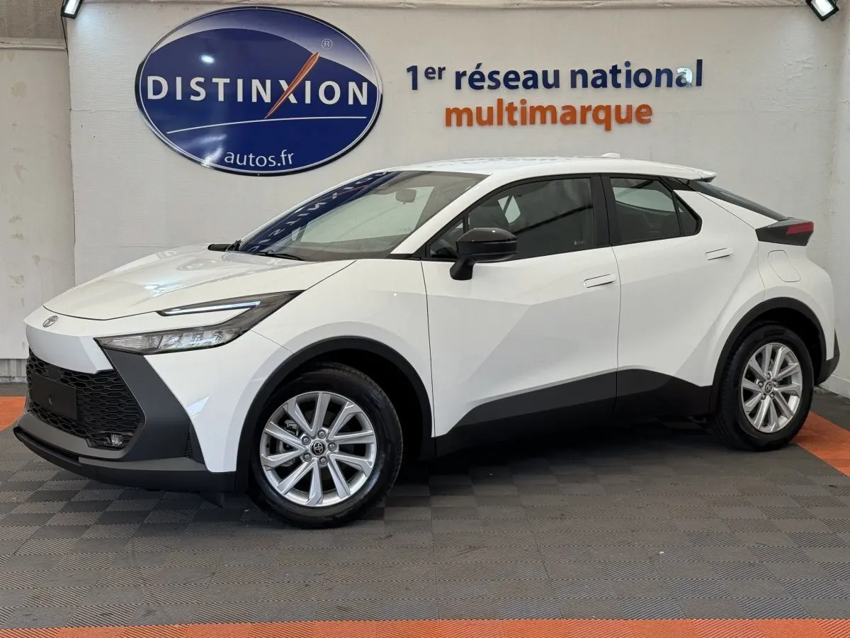 Toyota C-HR 1.8 Hybride blanc vu de profil côté gauche, avec jantes alliage et détails noirs contrastants.