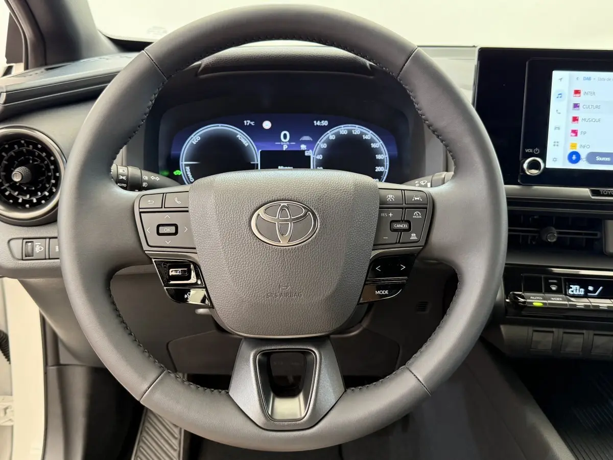 Vue intérieure centrée sur le volant cuir du Toyota C-HR 1.8 Hybride 140 Dynamic avec tableau de bord numérique.