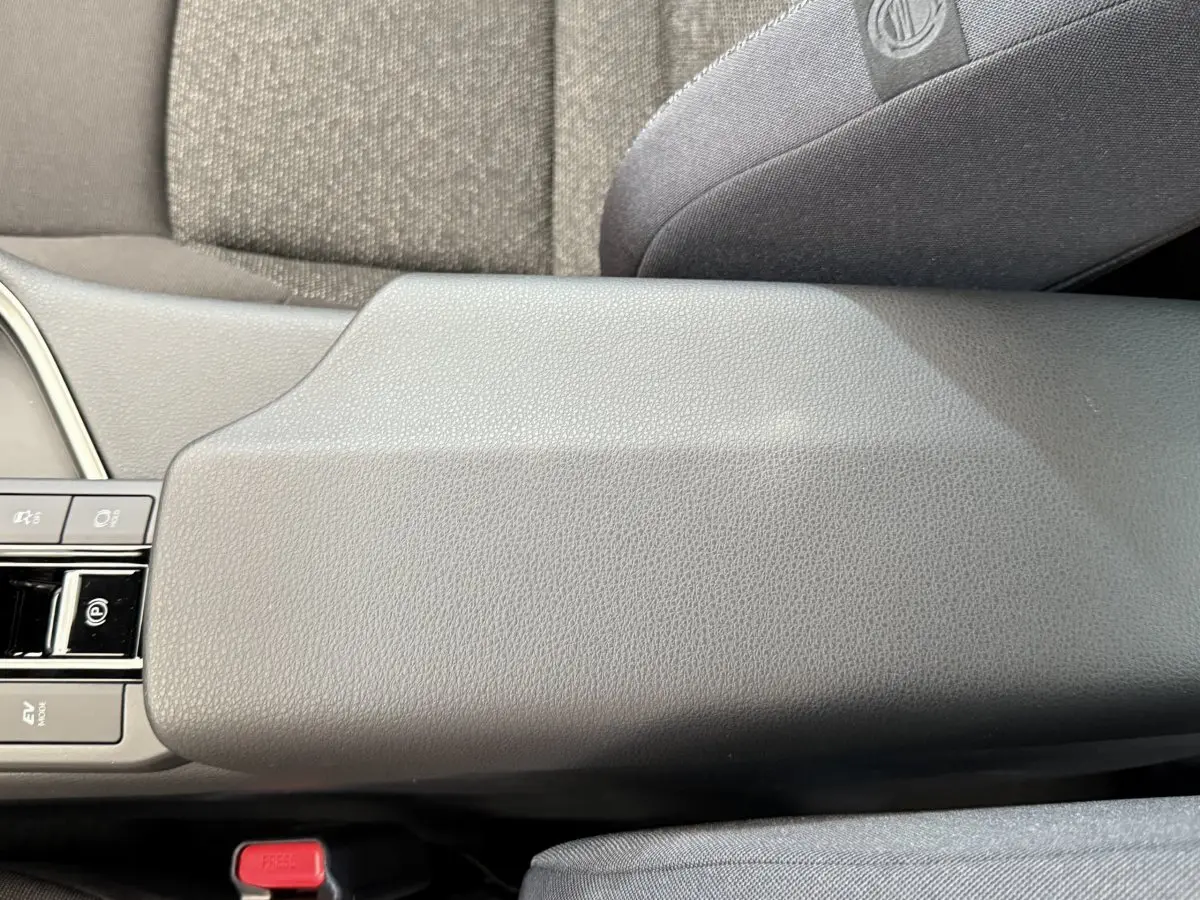 Accoudoir central gris clair en cuir avec commandes électroniques, intérieur du Toyota C-HR 1.8 Hybride 2024 vue de dessus