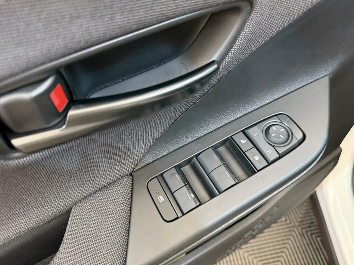Détail des commandes de lève-vitres et rétroviseurs sur la porte avant gauche d'un Toyota C-HR blanc 2024.