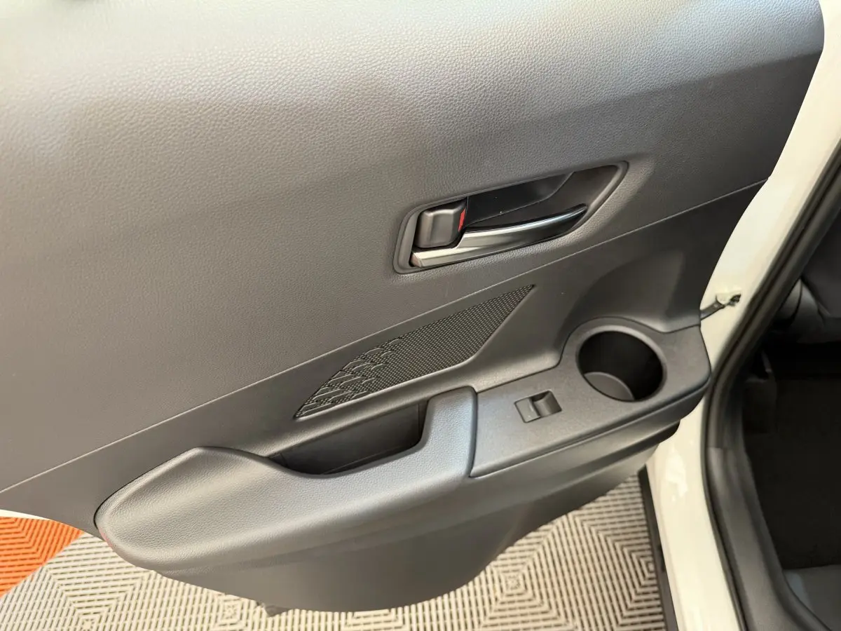 Gros plan sur la porte arrière droite noire avec poignée intérieure et porte-gobelet du Toyota C-HR blanc 2024.