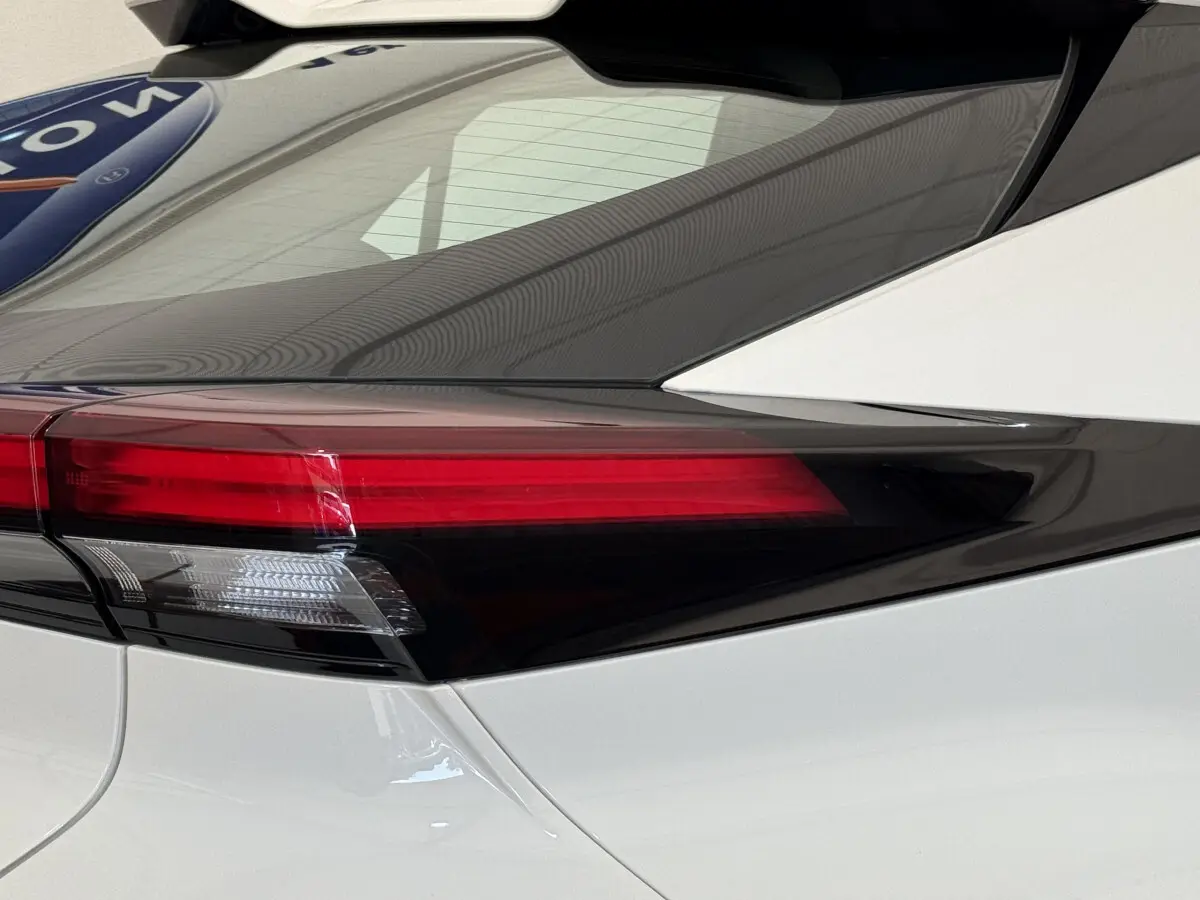 Gros plan sur le feu arrière gauche rouge et blanc du Toyota C-HR 1.8 Hybride blanc 2024, soulignant sa ligne épurée.