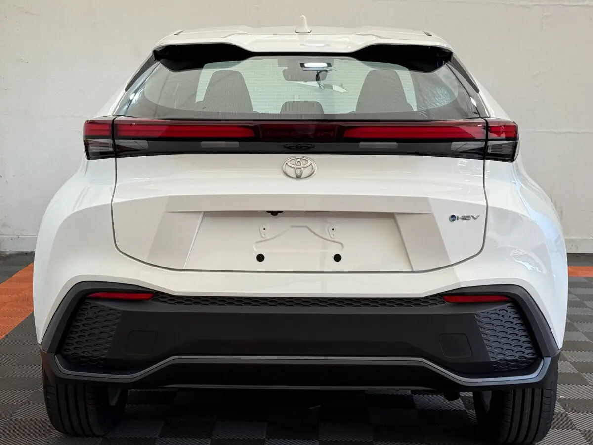 Vue arrière du Toyota C-HR blanc 2024 avec feux LED horizontaux et logo hybride HEV visible sur le coffre.