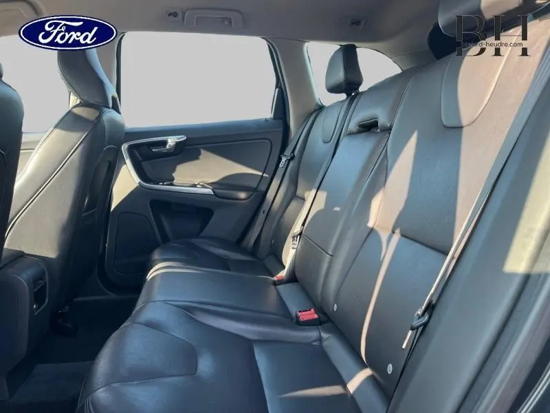 Vue intérieure côté droit montrant la banquette arrière en cuir noir du Volvo XC60 gris Savile, avec ceintures de sécurité visibles.