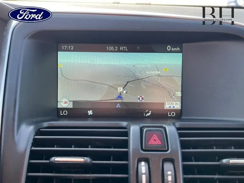 Écran de navigation couleur intégré au tableau de bord noir d’un Volvo XC60 gris Savile, vue intérieure frontale.