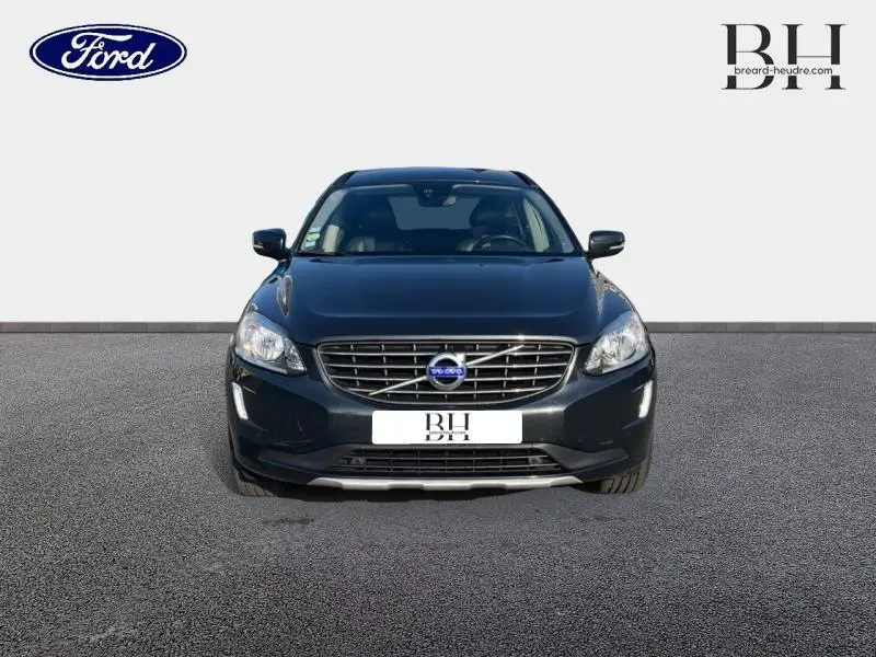 Vue avant d'un Volvo XC60 D3 150ch Momentum Business gris Savile avec calandre chromée et phares allumés.