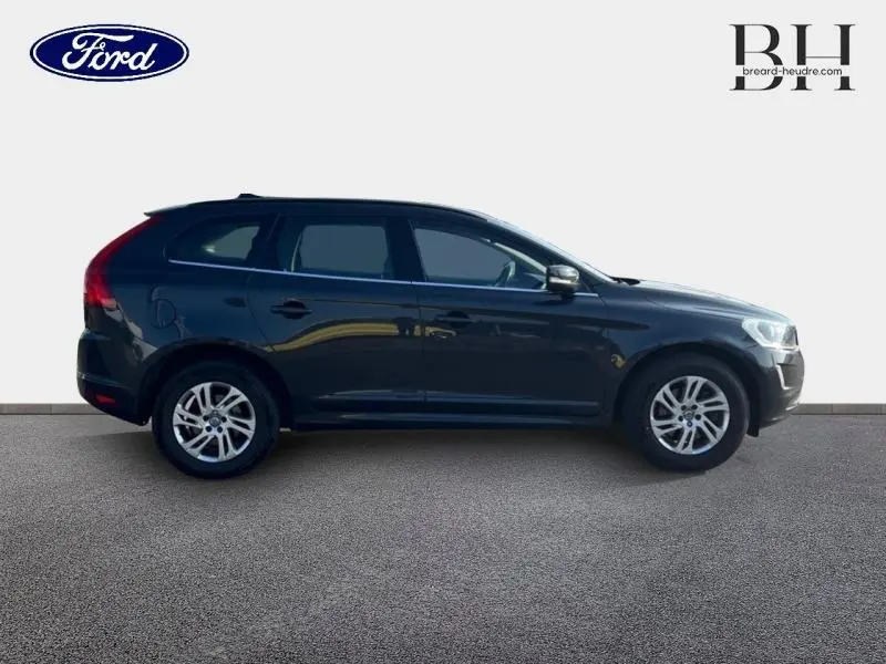 Profil droit d'un Volvo XC60 gris Savile de 2016, avec jantes alu et barres de toit visibles.