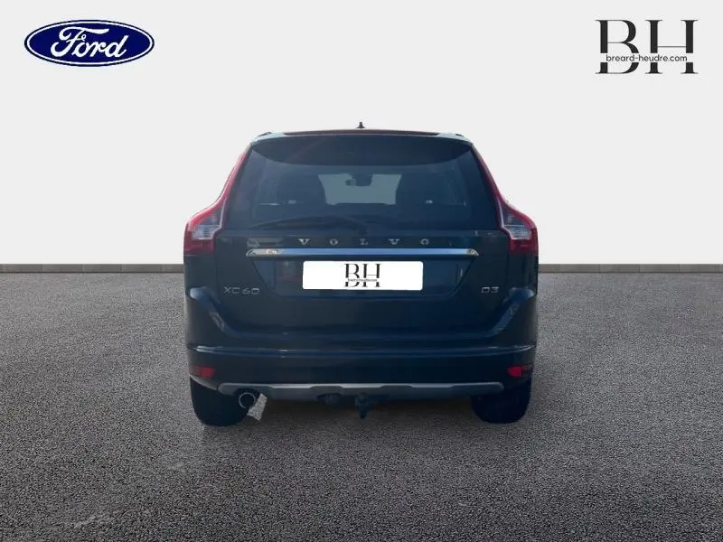 Vue arrière d'un Volvo XC60 D3 gris Savile, mettant en valeur ses feux arrière en forme de L et sa sortie d'échappement chromée.