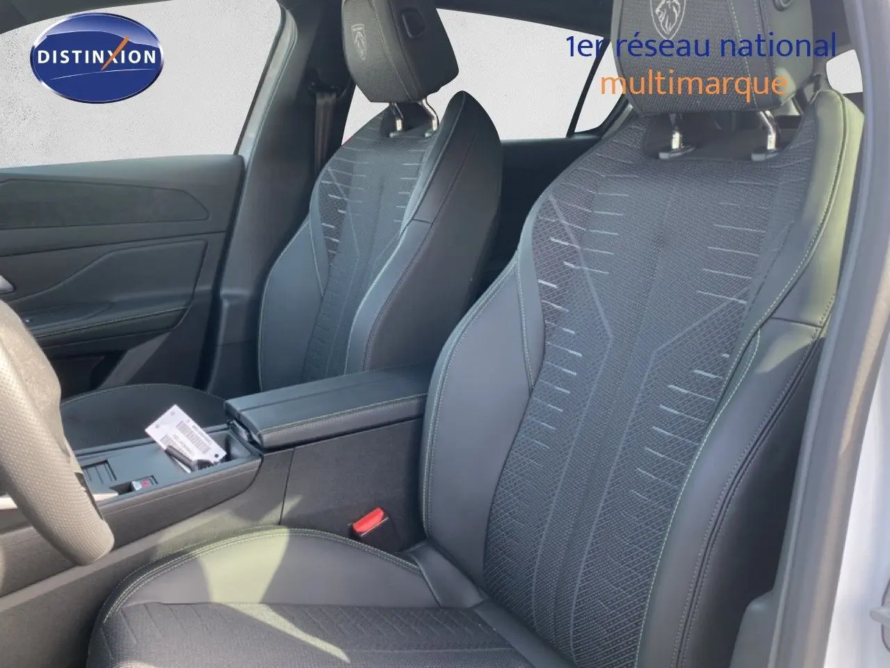 Vue intérieure côté droit montrant les sièges avant en tissu et cuir noir avec logo Peugeot brodé sur les appuie-têtes.