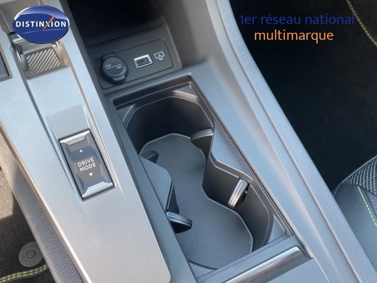 Vue rapprochée de la console centrale noire avec porte-gobelets et bouton Drive Mode dans une Peugeot 308 blanche.