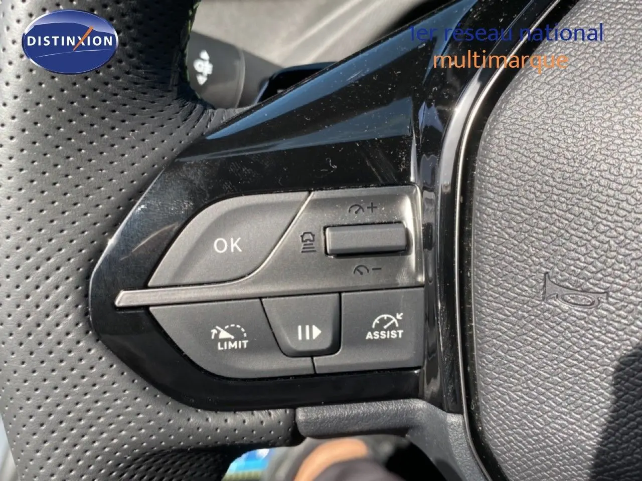 Gros plan sur les commandes de régulateur de vitesse au volant perforé noir d’une Peugeot 308 blanche.