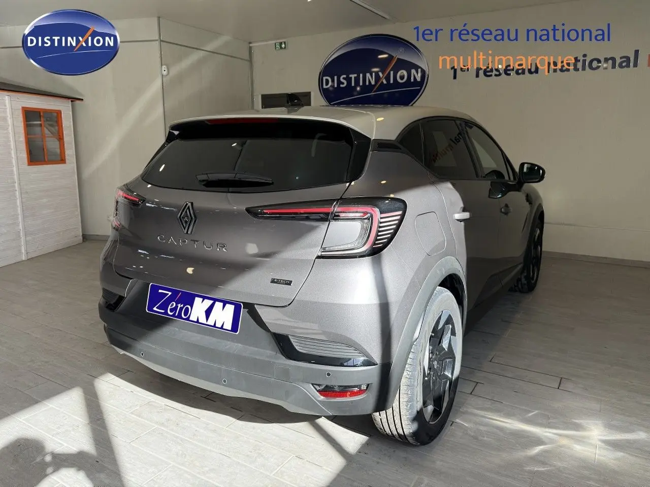 Vue 3/4 arrière droite d'un Renault Captur gris Cassiopée métal avec toit gris, en intérieur showroom.