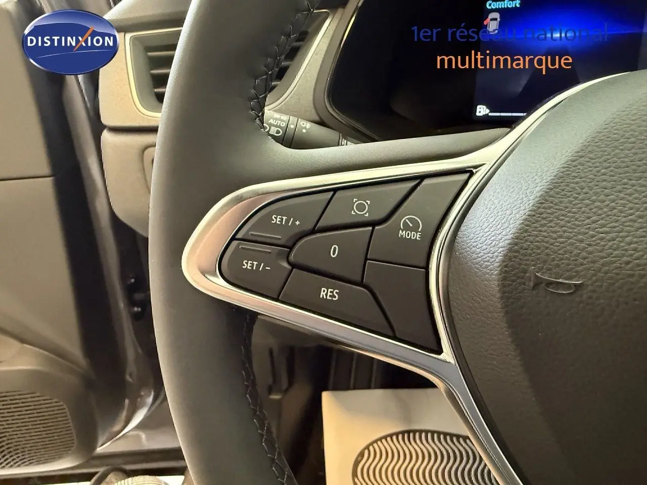 Gros plan sur les commandes au volant côté gauche du Renault Captur gris Cassiopée, affichage digital en arrière-plan.