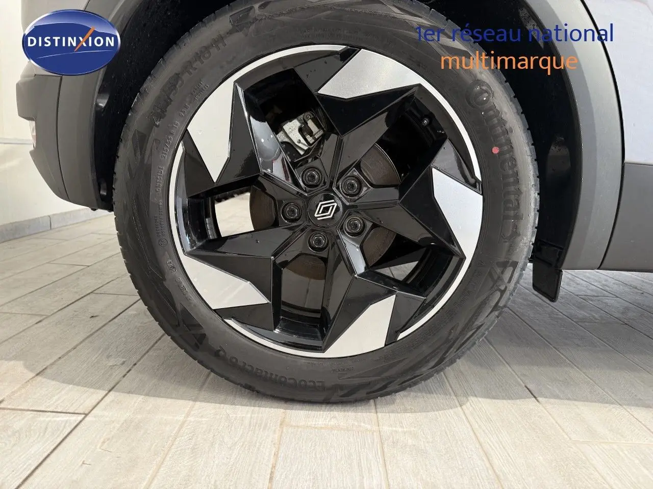 Gros plan sur la roue avant droite du Renault Captur gris Cassiopée, jante alliage noire et argentée au design géométrique.