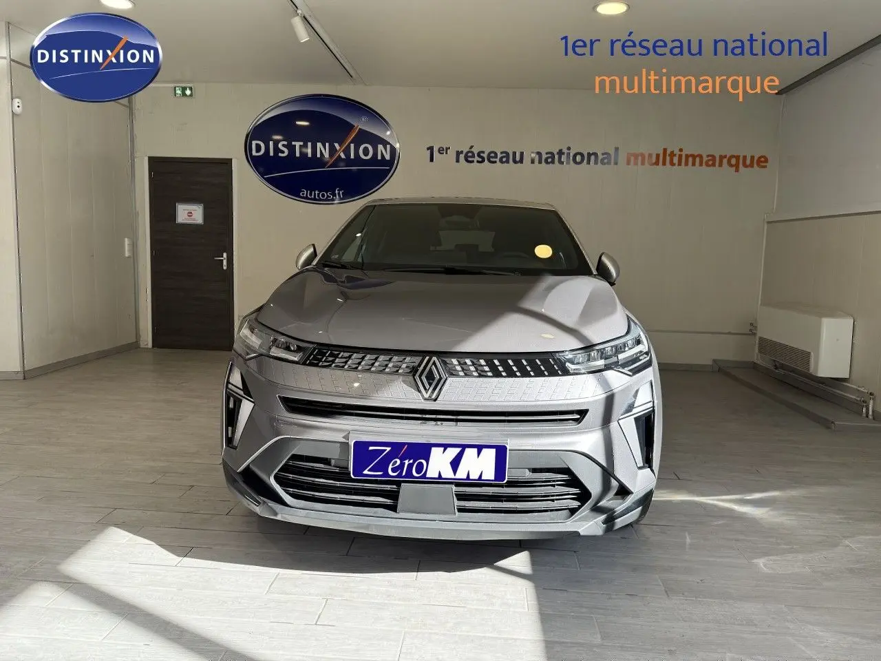 Vue frontale d'un Renault Captur gris Cassiopée métal avec toit gris, dans un showroom lumineux.