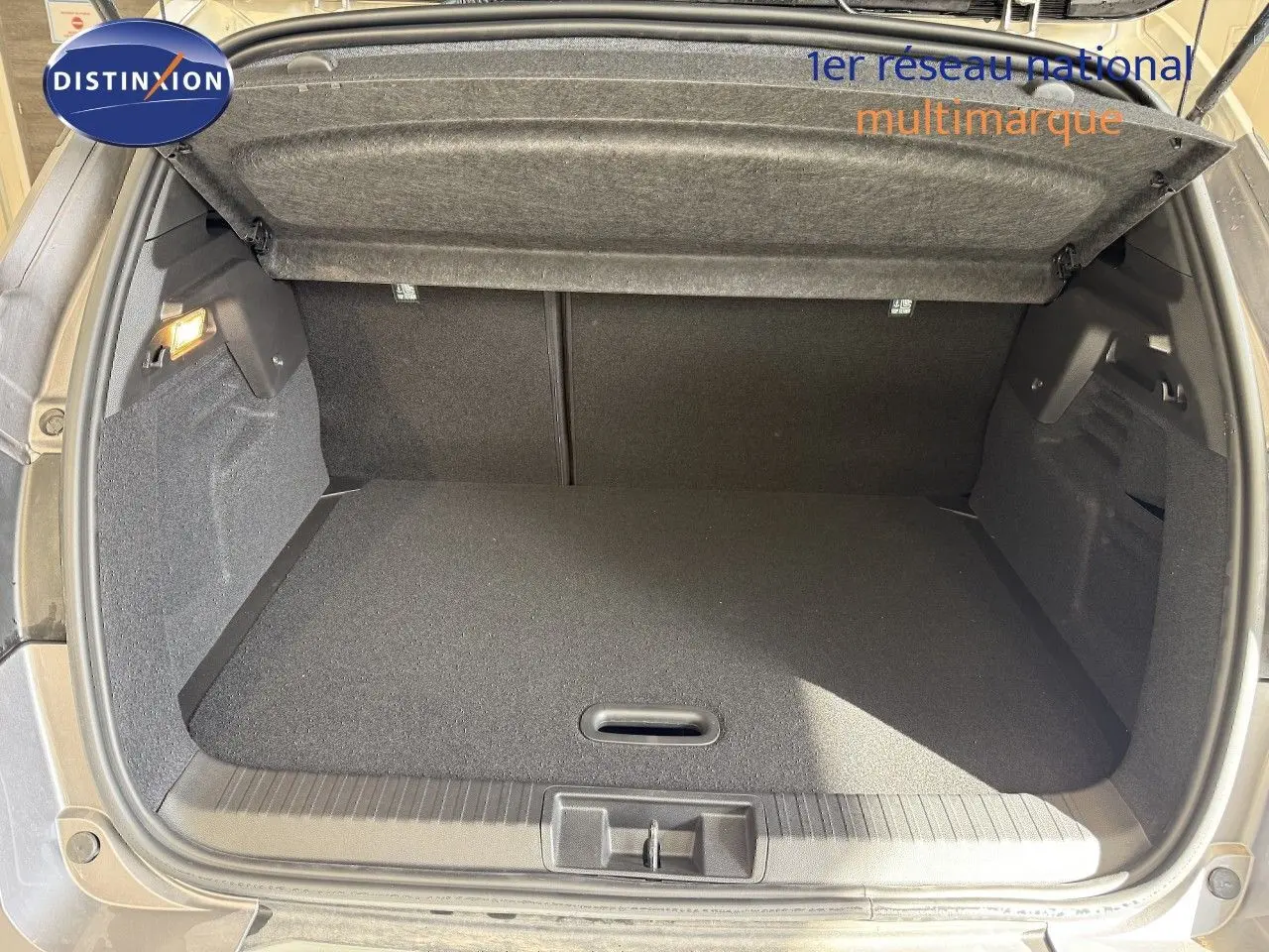 Coffre ouvert vu de l'arrière du Renault Captur gris Cassiopée métal avec intérieur de coffre noir et cache-bagages relevé.