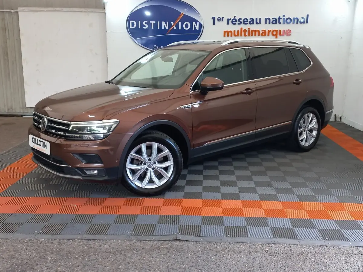 Volkswagen Tiguan Allspace marron vue de profil côté gauche en intérieur avec jantes alliage et toit chromé.