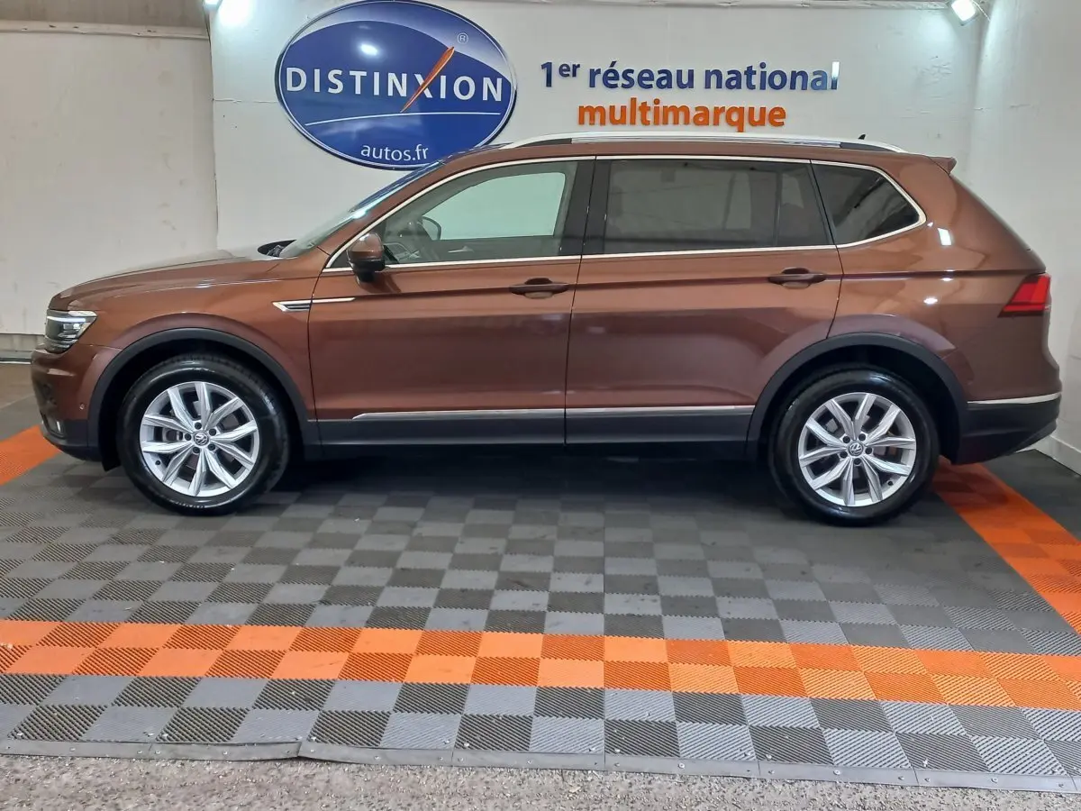 Profil côté gauche d'un Volkswagen Tiguan Allspace marron 2018 garé en intérieur sur sol gris et orange.