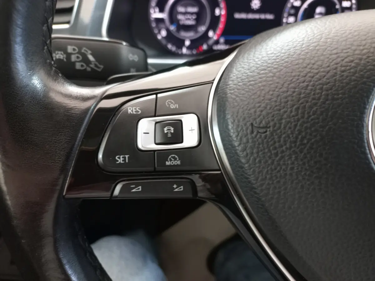 Gros plan sur les commandes du volant cuir noir du Volkswagen Tiguan Allspace 2018, avec affichage numérique en arrière-plan.