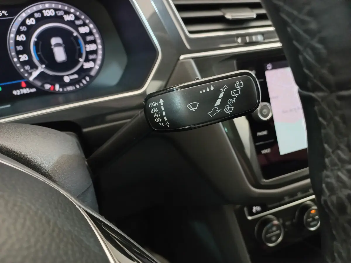 Gros plan sur la commande des essuie-glaces à gauche du volant dans l'habitacle noir du Volkswagen Tiguan Allspace marron 2018.