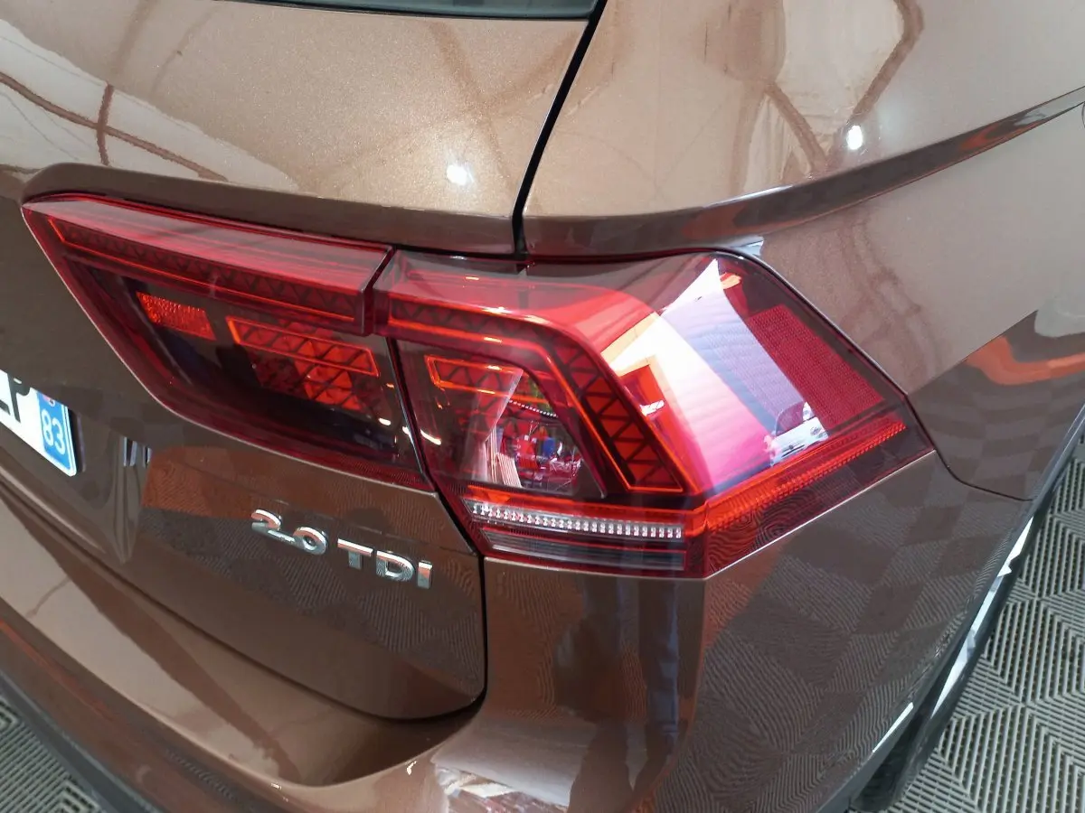 Gros plan sur le feu arrière droit marron métallisé du Volkswagen Tiguan Allspace 2.0 TDI 150 DSG7 avec logo visible.