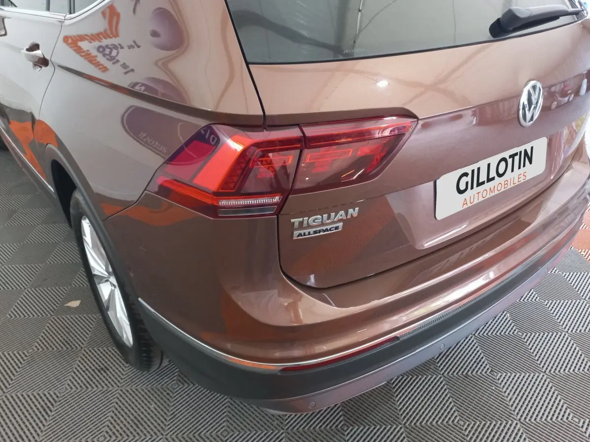 Vue 3/4 arrière droite d'un Volkswagen Tiguan Allspace marron avec feux arrière LED et logo visible