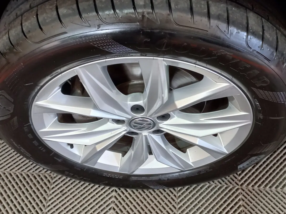 Gros plan sur la jante argentée avec logo Volkswagen d'un Tiguan Allspace marron, pneu Goodyear visible.