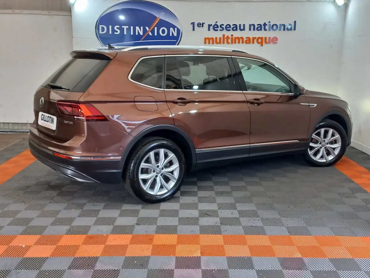 Vue latérale droite du Volkswagen Tiguan Allspace marron 2018 en intérieur, soulignant ses jantes alliage et lignes élégantes.