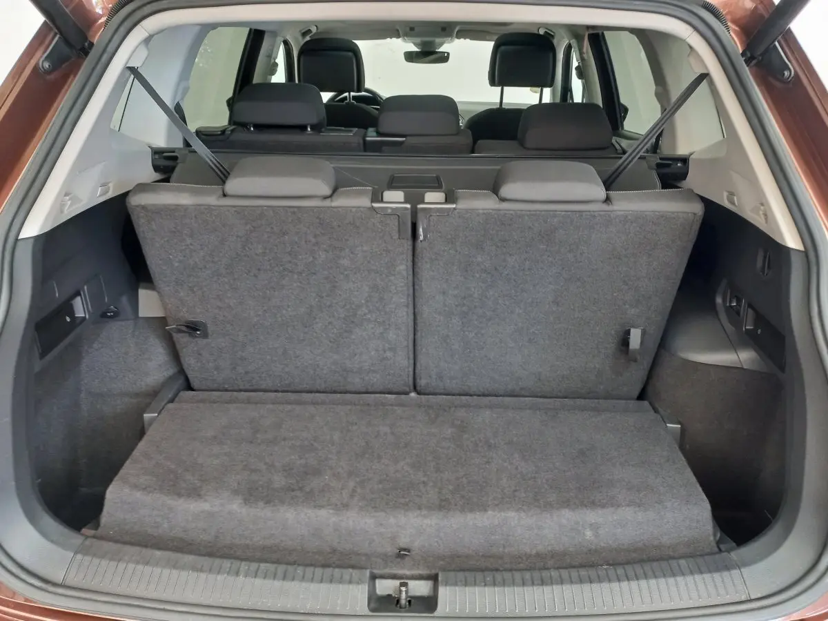 Vue arrière du coffre du Volkswagen Tiguan Allspace marron 2018 avec troisième rangée de sièges rabattus en tissu gris.