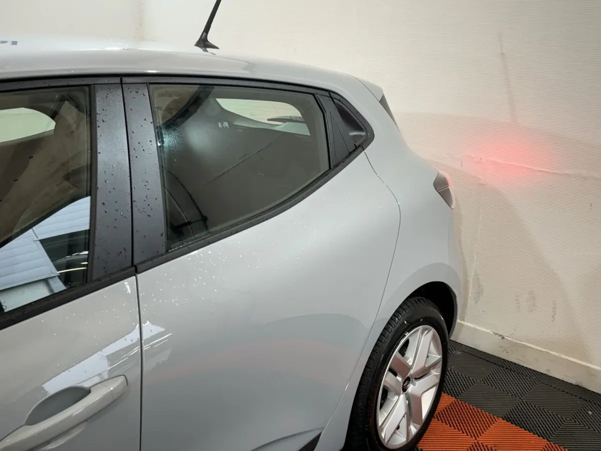 Vue côté arrière droit d'une Renault Clio gris clair 2025, avec jante alliage et antenne de toit visible.