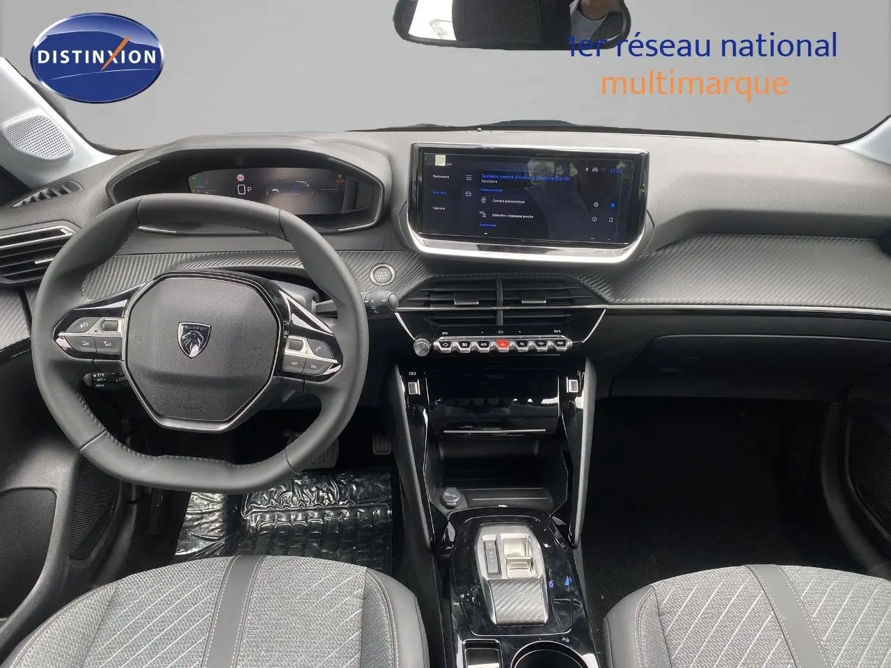 Vue intérieure avant du tableau de bord de la Peugeot 208 Hybrid 110ch avec volant compact et écran tactile central.