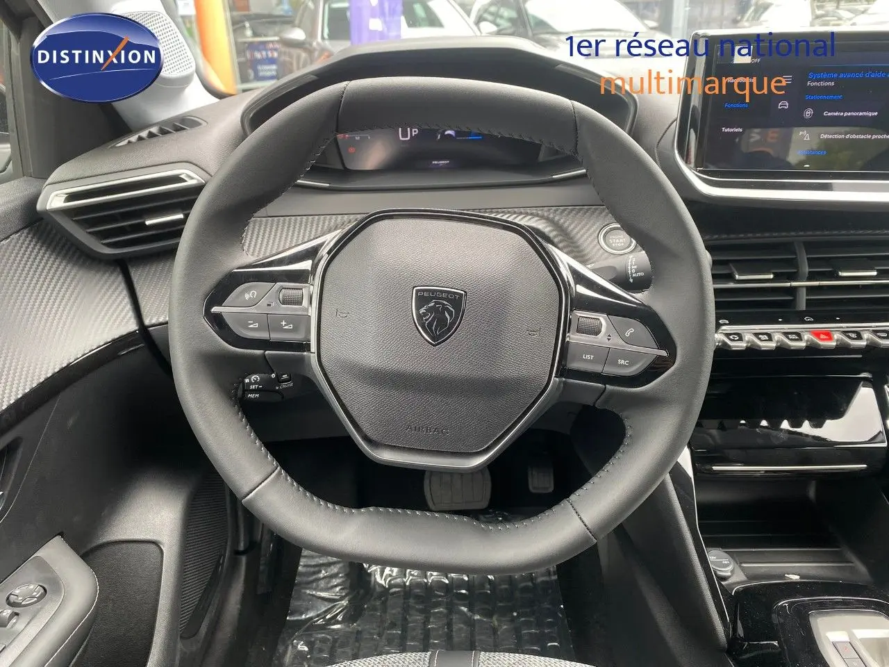 Vue centrée sur le volant cuir noir de la Peugeot 208 Hybrid 2026 avec tableau de bord et écran tactile visibles.