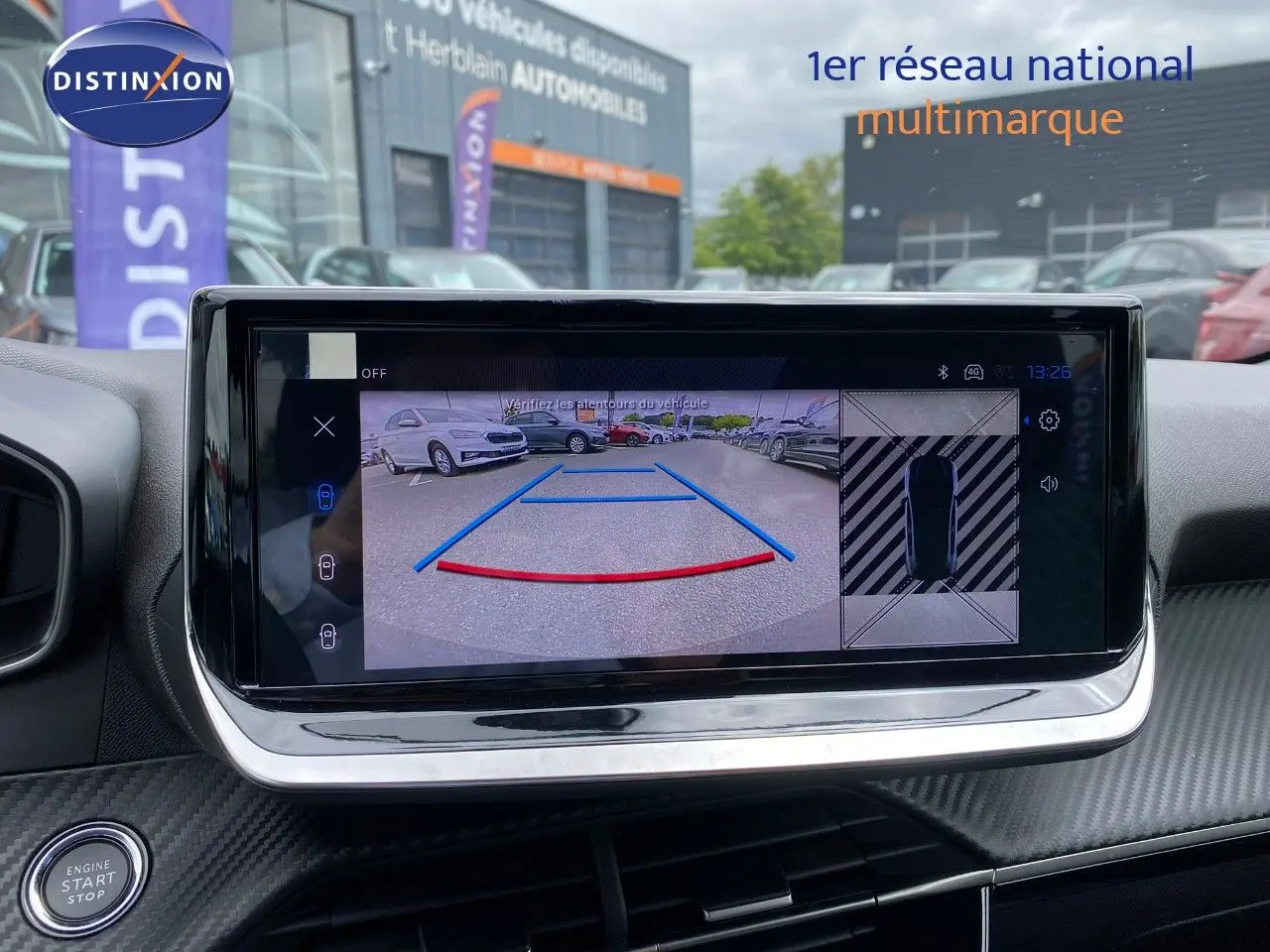 Écran tactile intérieur montrant la caméra de recul d'une Peugeot 208 gris selenium metal en stationnement.