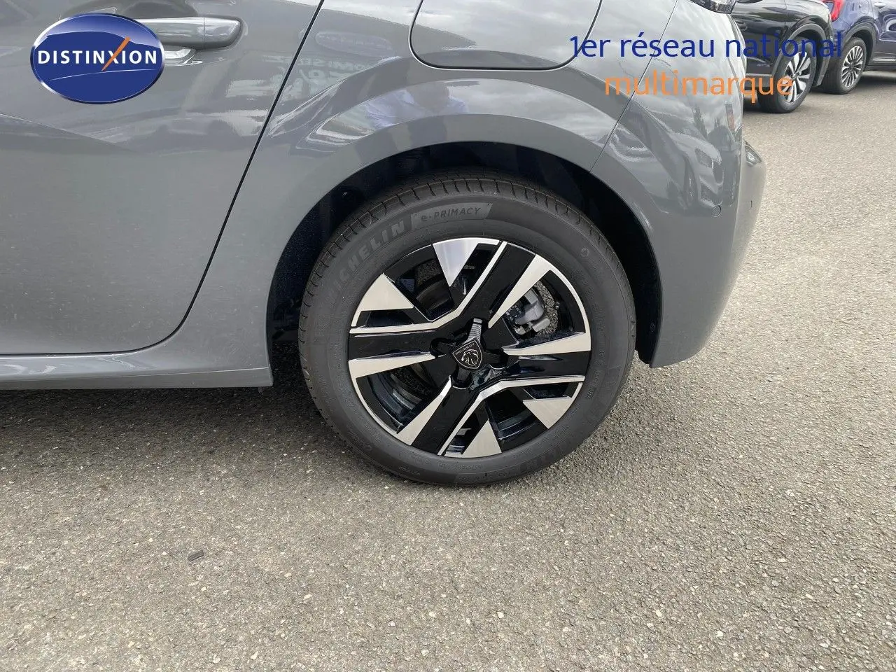Vue rapprochée sur la roue arrière gauche d'une Peugeot 208 gris selenium métal, mettant en valeur la jante noire et argentée.