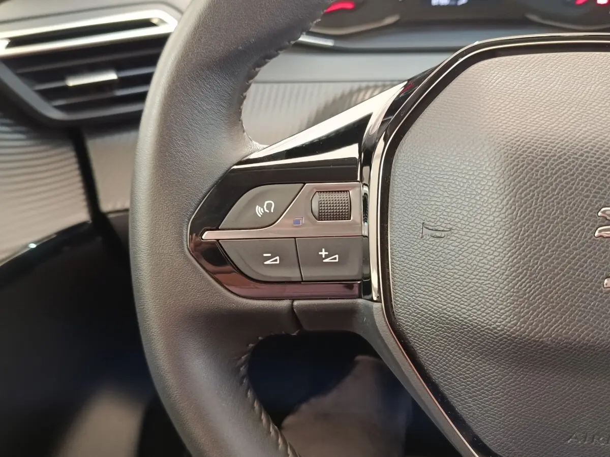 Gros plan sur le volant cuir noir de la Peugeot 208 PureTech 75 S&S Style 2023 avec commandes multifonctions.