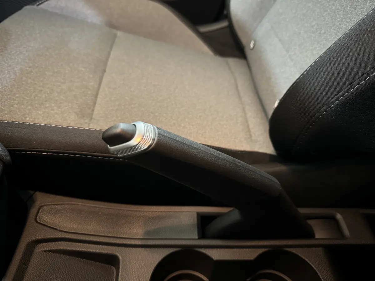 Le levier de frein à main noir en gros plan sur la console centrale, siège avant gris clair de la Renault Clio 2025.