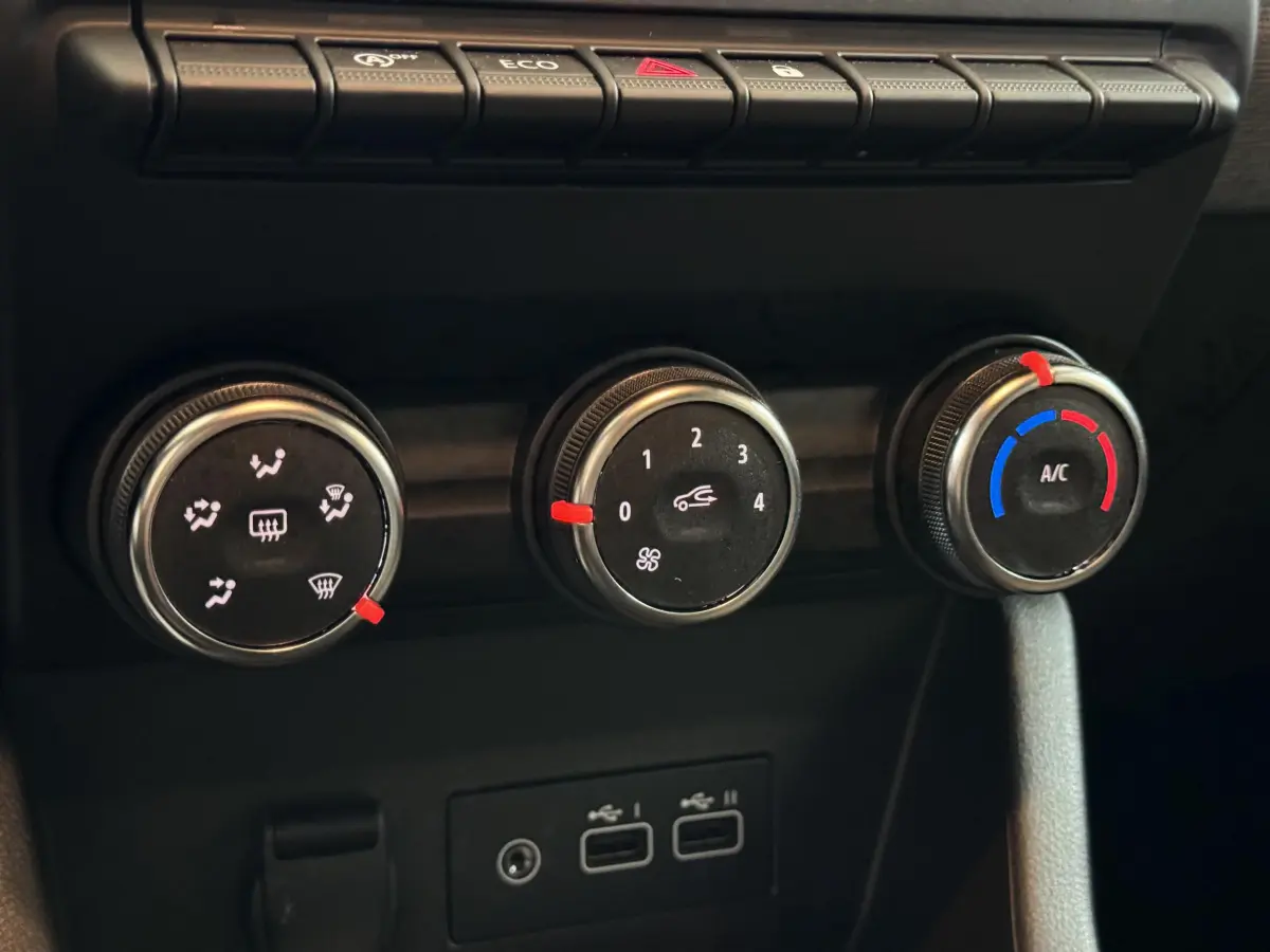 Gros plan sur les commandes de climatisation et ports USB du tableau de bord noir de la Renault Clio gris clair 2025.
